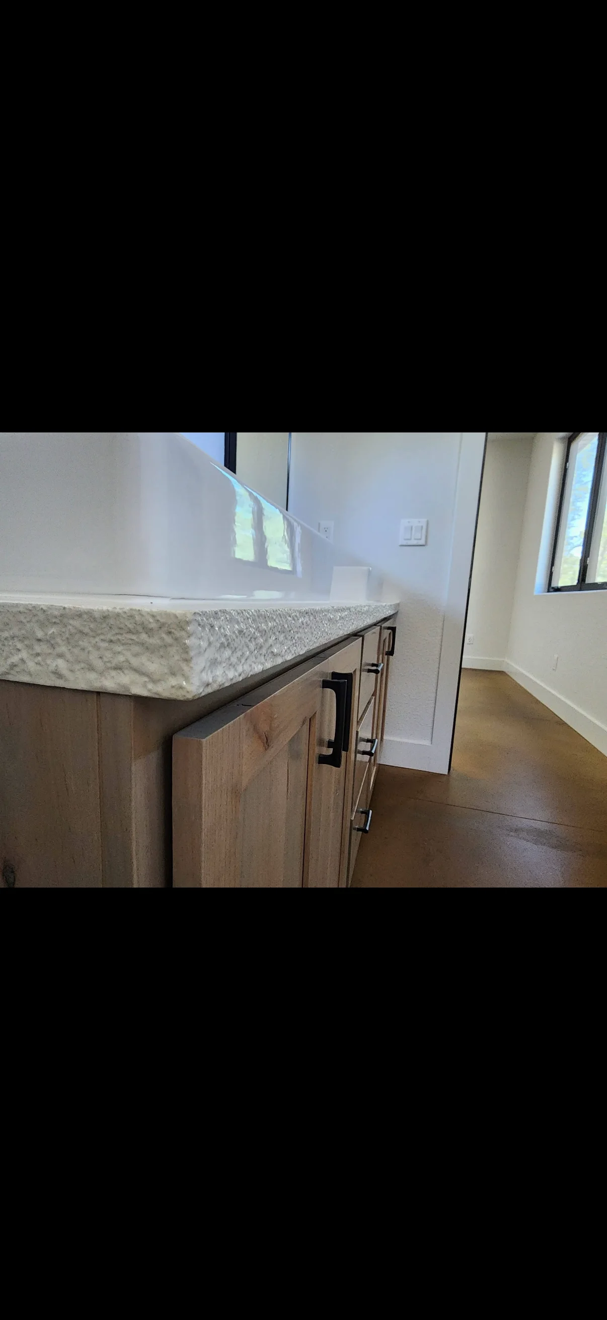 Stone countertop with textured finish on stained wood cabinetry and modern pulls in kitchen