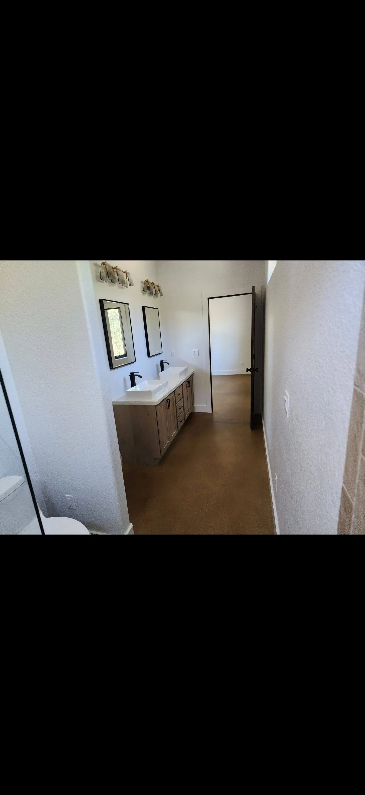 Dual sink vanity with wood cabinetry, quartz countertop, and black-framed mirrors in renovated bathroom