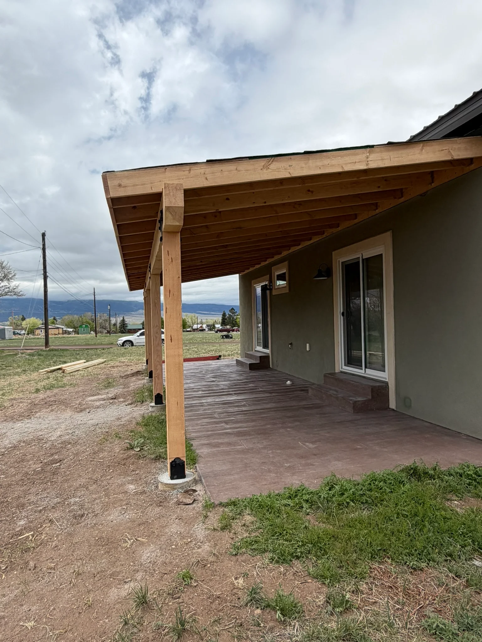 Wood beam covered patio with composite deck and metal roof trim attached to home